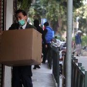 Man in mask carrying box outside building